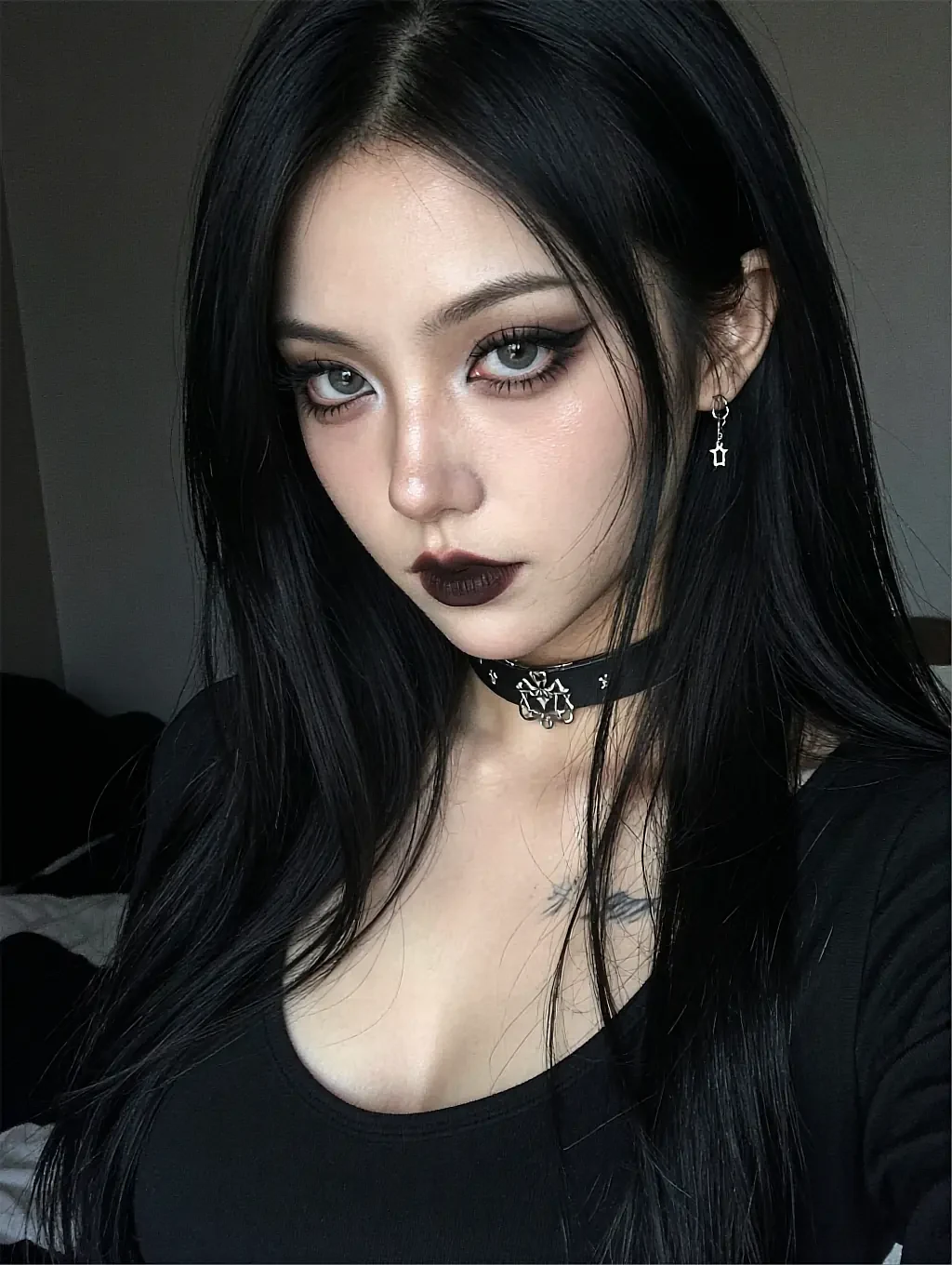 Fictional AI character with a small collarbone tattoo and a black choker, photographed in a low-lit bedroom